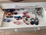 many pairs of sunglasses in the drawer of a dresser