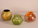 three different colored vases sitting next to each other on a white surface