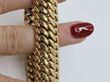 someone is holding a gold chain bracelet and a red manicure