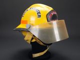 yellow firefighter helmet with visor on display against a black background