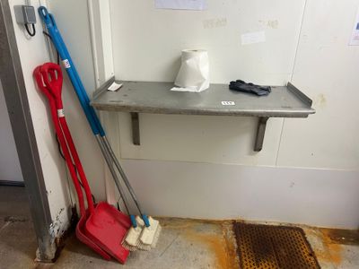 deux balais et une serpillière posés sur une étagère dans une pièce