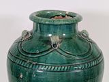 a green vase with a handle on a white surface