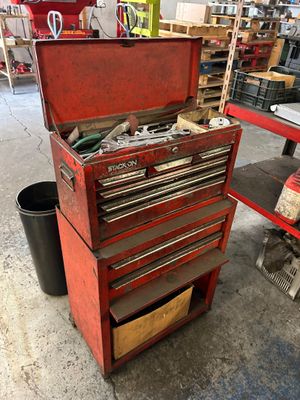 une caisse à outils rouge, sur laquelle sont posés des outils, dans un garage