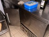 un plan de travail en acier inoxydable dans une cuisine professionnelle, sur lequel sont posées des bouteilles de vin