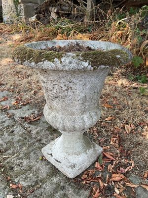 un vase en pierre recouvert de mousse, posé à même le sol
