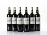 six bottles of wine are lined up in a row on a white surface