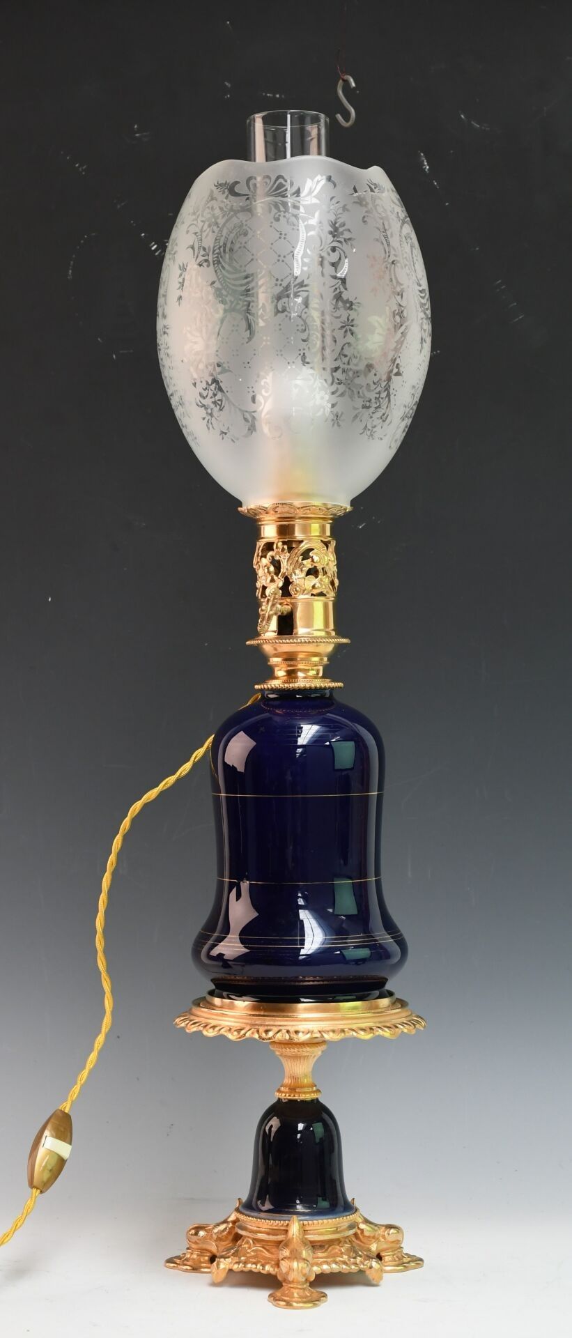 Lampe à huile montée à l'électricité en porcelaine émaillée bleue à décor de filets dorés, monture en laiton doré. El...