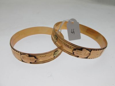 pair of gold tone bracelets with engraved designs on them