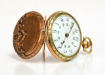 une montre de poche en or posée sur une surface blanche