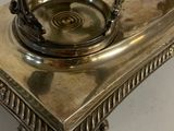 a silver plate on a stand with a clock on it