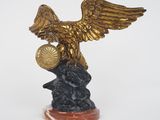 une statue représentant un aigle tenant une boule au sommet d'un rocher