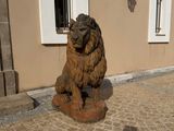 a statue of a lion sitting on a stone block in front of a building