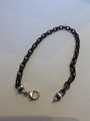 un gros plan sur un bracelet à maillons noirs muni d'un fermoir en argent