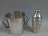 une tasse en argent et un shaker en argent posés sur une table