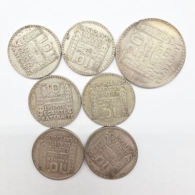 six pièces d'argent de formes et de tailles différentes sur un fond blanc