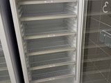 two empty refrigerators in a room with tile flooring