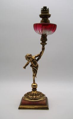 un bougeoir ancien en laiton avec un abat-jour en verre rouge