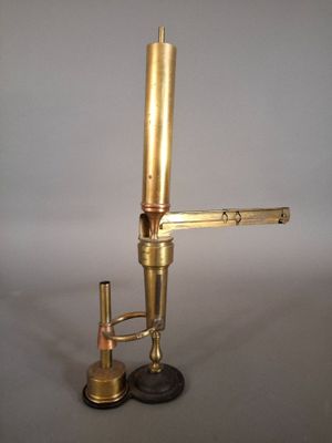 un microscope ancien en laiton, avec un socle noir et une poignée dorée