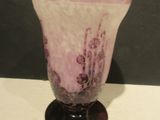 un vase violet posé sur une table, sur fond noir