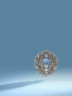 a close up of a brooch with a blue stone surrounded by diamonds