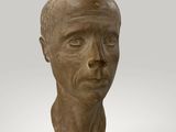 a close up of a sculpture of a man ' s head on a wooden base