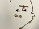 un ensemble composé d'un collier et de boucles d'oreilles en or, posé sur une surface blanche
