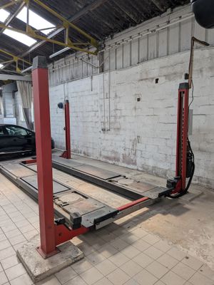 une image montrant une voiture garée dans un garage équipé d'un pont élévateur