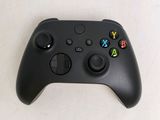 a close up of a black xbox controller on a white surface