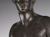 a bronze statue of a young man holding a tennis racquet
