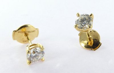 two pairs of diamond stud earrings on a white surface