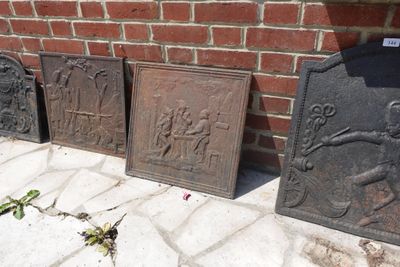 trois plaques en fonte posées sur le trottoir, à côté d'un mur de briques