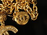 a close up of a gold chain with a chanel charm on it