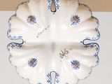 a white plate with blue flowers on it hanging from the ceiling