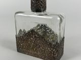 a small glass bottle with a metal decoration on it