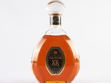 une photo d'une bouteille de brandy posée sur une surface blanche