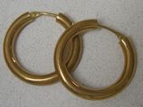 paire de boucles d'oreilles créoles dorées sur fond blanc