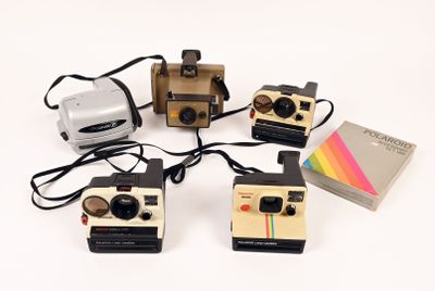 several polaroid cameras are lined up on a white surface