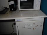 un micro-ondes posé sur un petit réfrigérateur blanc