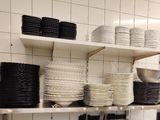 many plates and bowls stacked on the shelves in the kitchen