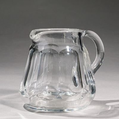 a clear glass pitcher with a handle on a table