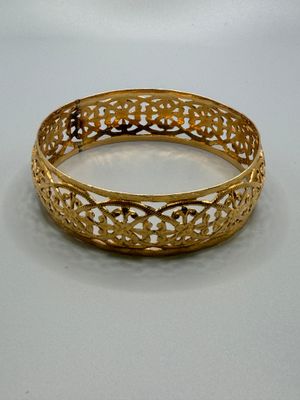 gros plan d'un bracelet en or sur une surface blanche