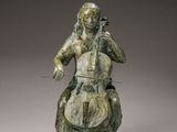 statue en bronze représentant une femme jouant du violoncelle sur un rocher