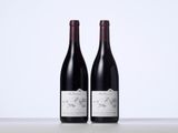two bottles of red wine sitting on top of a table