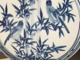a blue and white plate with birds on it on a table