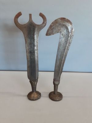 une paire de vieilles épées en métal posées sur une surface blanche, sur fond bleu