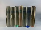 five books are lined up in a row on a white surface