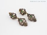 a pair of emerald and diamond earrings on a white surface