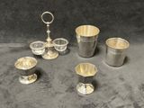 quatre tasses en argent et une cuillère en argent posées sur une table