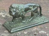 une statue en bronze représentant un lion sur un socle