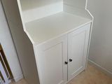 a white cabinet with a book shelf in the corner of the room